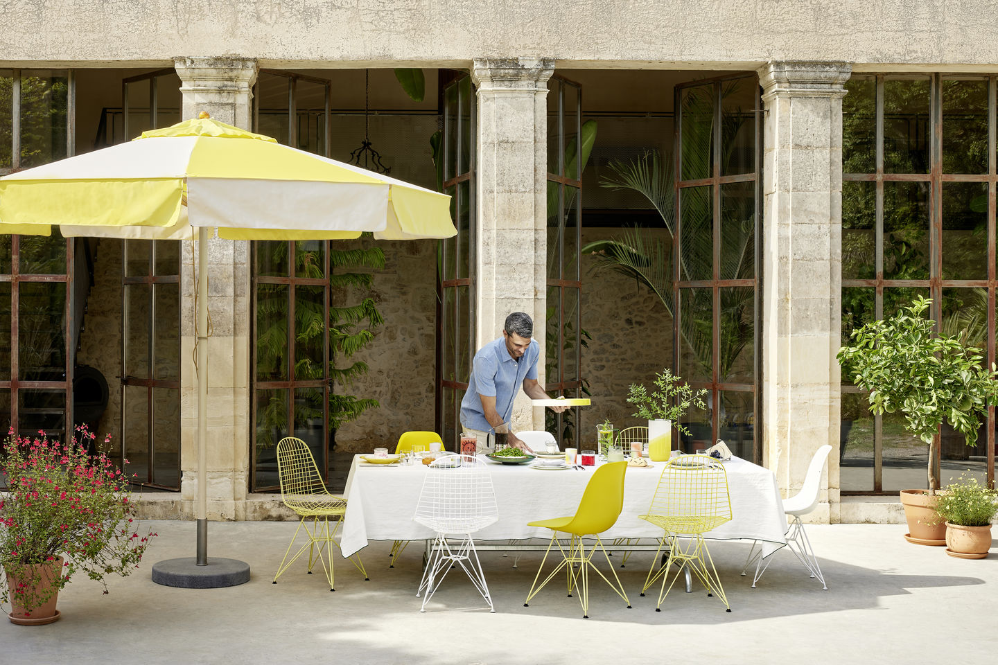 Esstisch im Freien mit Eames Plastic Side Chairs DSR von Vitra in Gelb und Weiß.