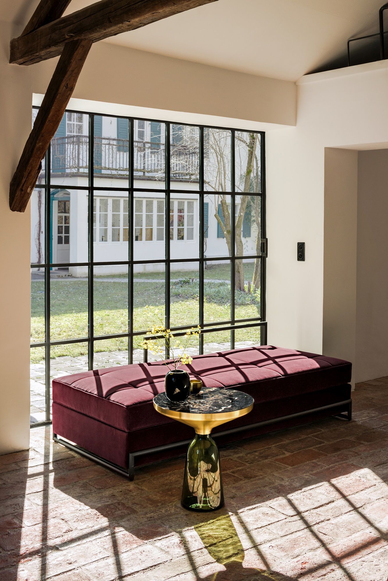 Day Bed Grand Liege Classicon in bordeauxrotem Samt vor Fenster mit Blick in den Garten.