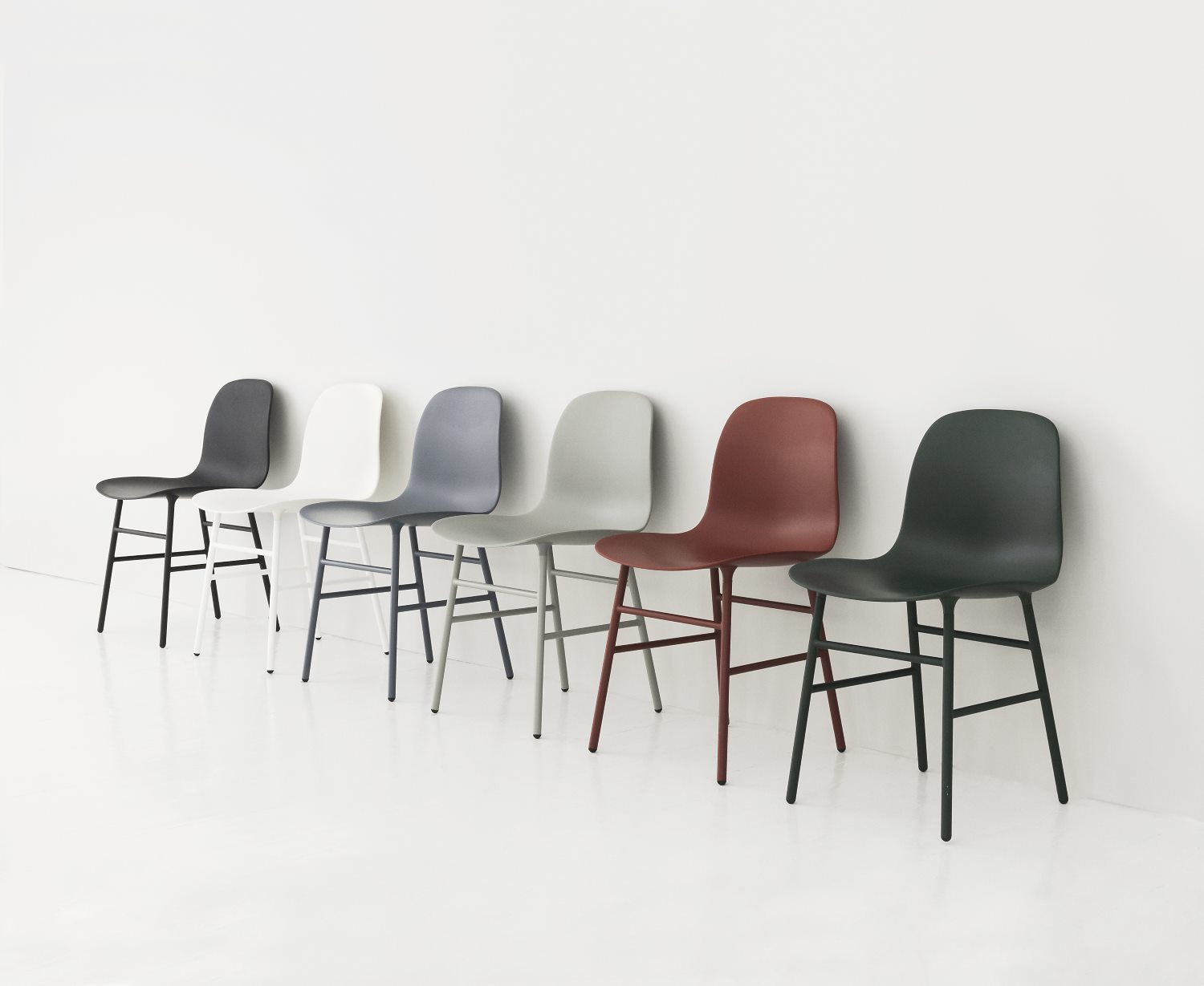 Reihe von Form Stühlen von Normann Copenhagen in verschiedenen Farben vor einer weißen Wand.