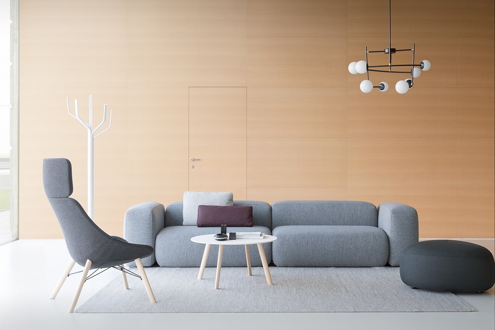 Grauer PLUS D210 Pouf/Sessel La Palma in modernem Wohnzimmer mit Sofa und Teppich.
