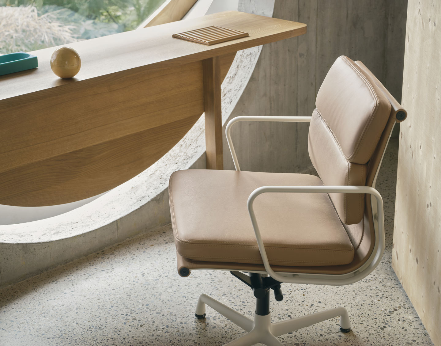 Beiger Soft Pad Chair EA 231 von Vitra mit weißem Gestell und Armlehnen vor Fenster.