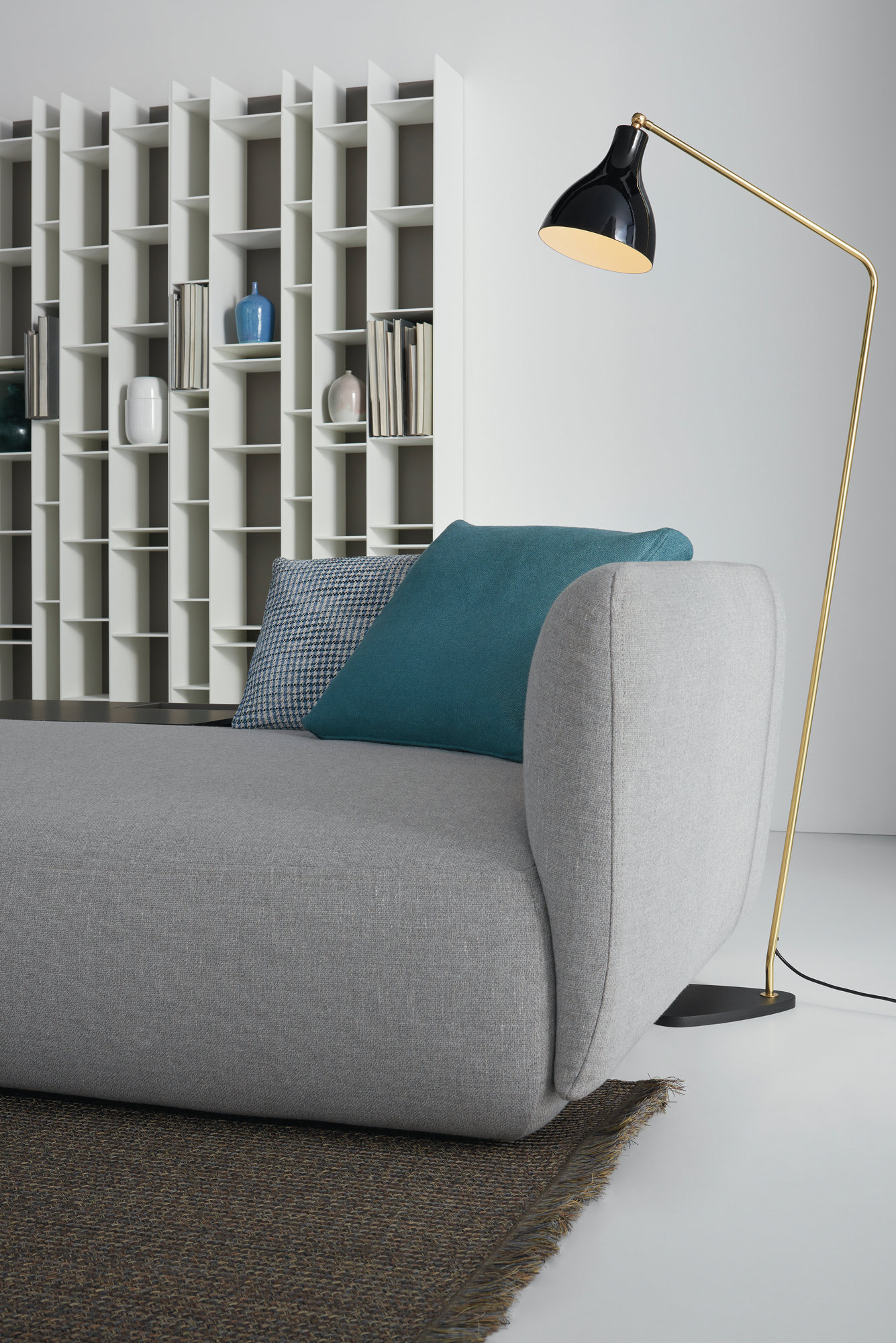Nahaufnahme des grauen Cosy Sofa von MDF Italia mit Kissen und Stehlampe.