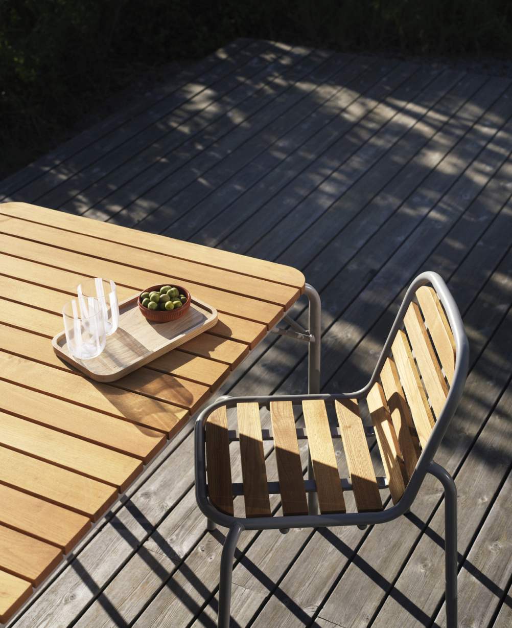 Nahaufnahme des Vig Chair Wood Stuhls von Normann Copenhagen im Außenbereich mit Holztisch und Oliven.