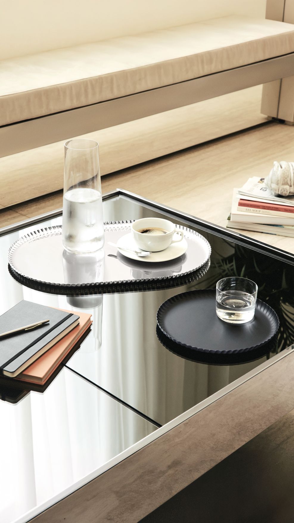 JK01/46 Pleats Tablett von Alessi auf einem Tisch mit Wasserglas und Kaffeetasse.