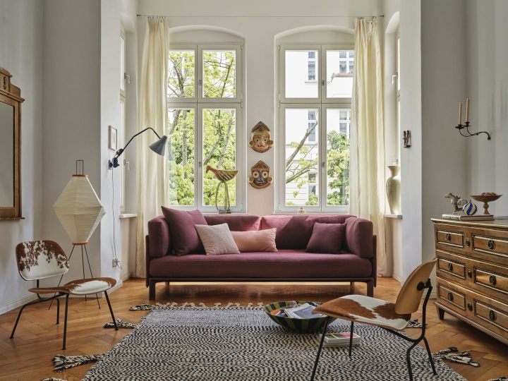 Wohnzimmer mit burgunderrotem Sofa und Vitra Anagram Panel 90 cm an der Wand.