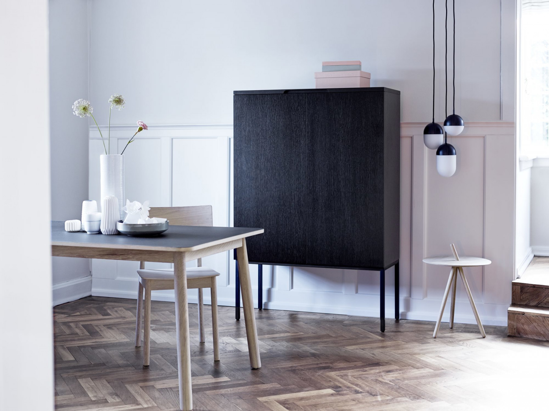 Esszimmer mit Esstisch, Stuhl, schwarzem Holzschrank, Beistelltisch und Pendelleuchten im modernen skandinavischen Design.
