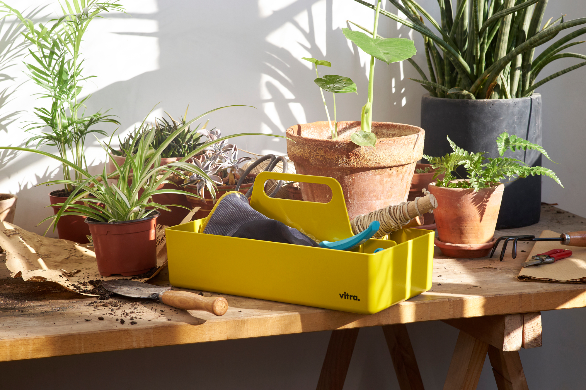 Gelbe Vitra Toolbox Organisationsbox mit Gartenzubehör und Pflanzen auf einem Holztisch, ideal für Gartenarbeit und Aufbewahrung.
