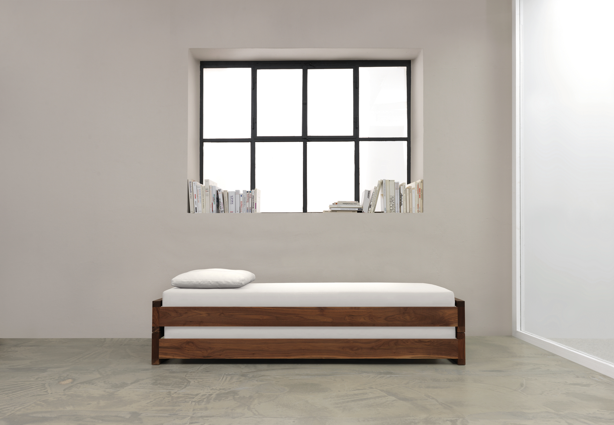 Guest 90 Holzbett: Modernes Einzelbett aus massivem Nussbaumholz mit weißer Matratze und Kissen.