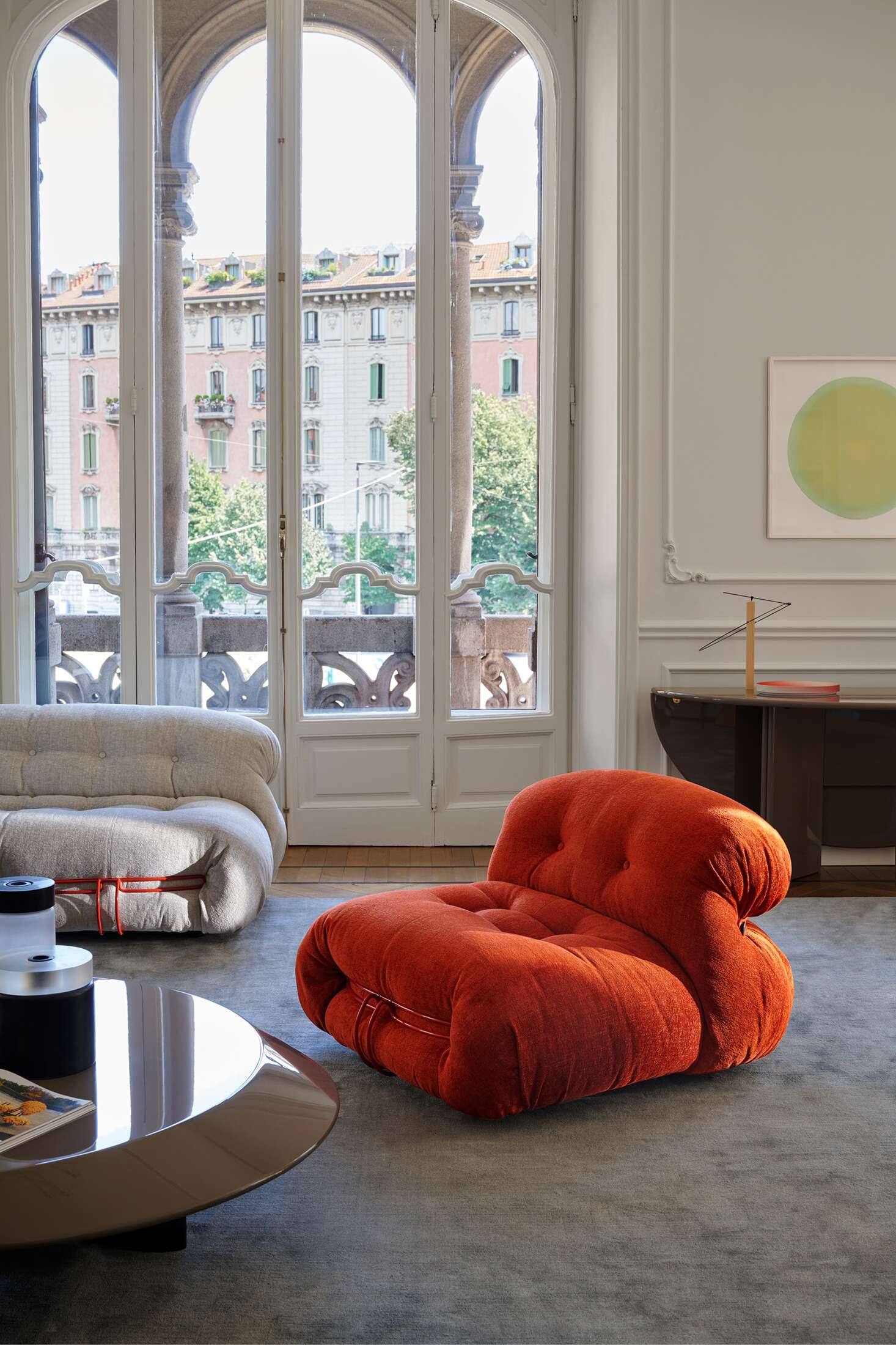 Oranger Cassina Soriana Sessel im modernen Wohnzimmer mit großem Fenster und Designermöbeln. Bequemer Sessel für stilvolles Wohnen.