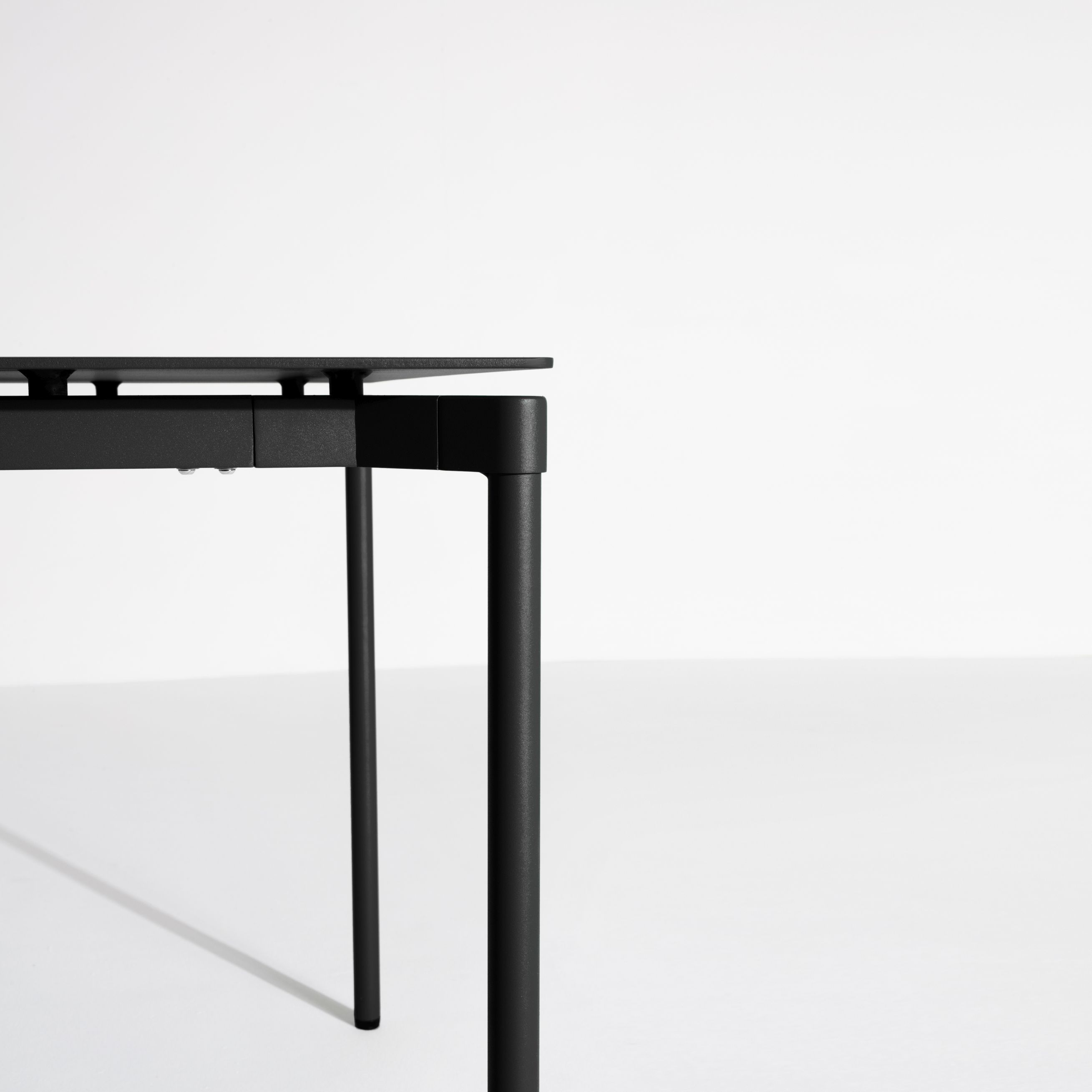Detailaufnahme des Fromme Esstischs von Petite Friture: Rechteckige Tischplatte und Tischbeine in Schwarz.