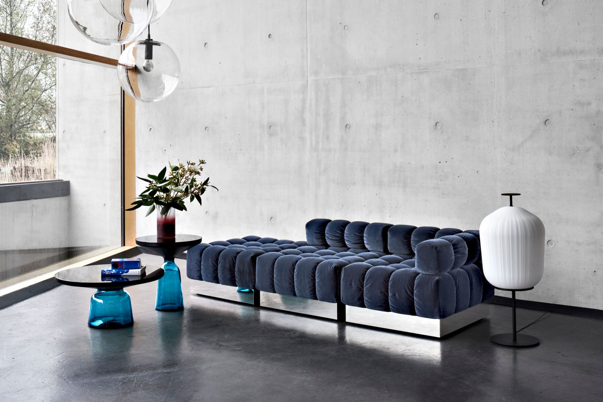 Wohnzimmer Interieur mit blauem Modulsofa und Bell Table Beistelltisch von Classicon, sowie einer weißen Stehlampe.