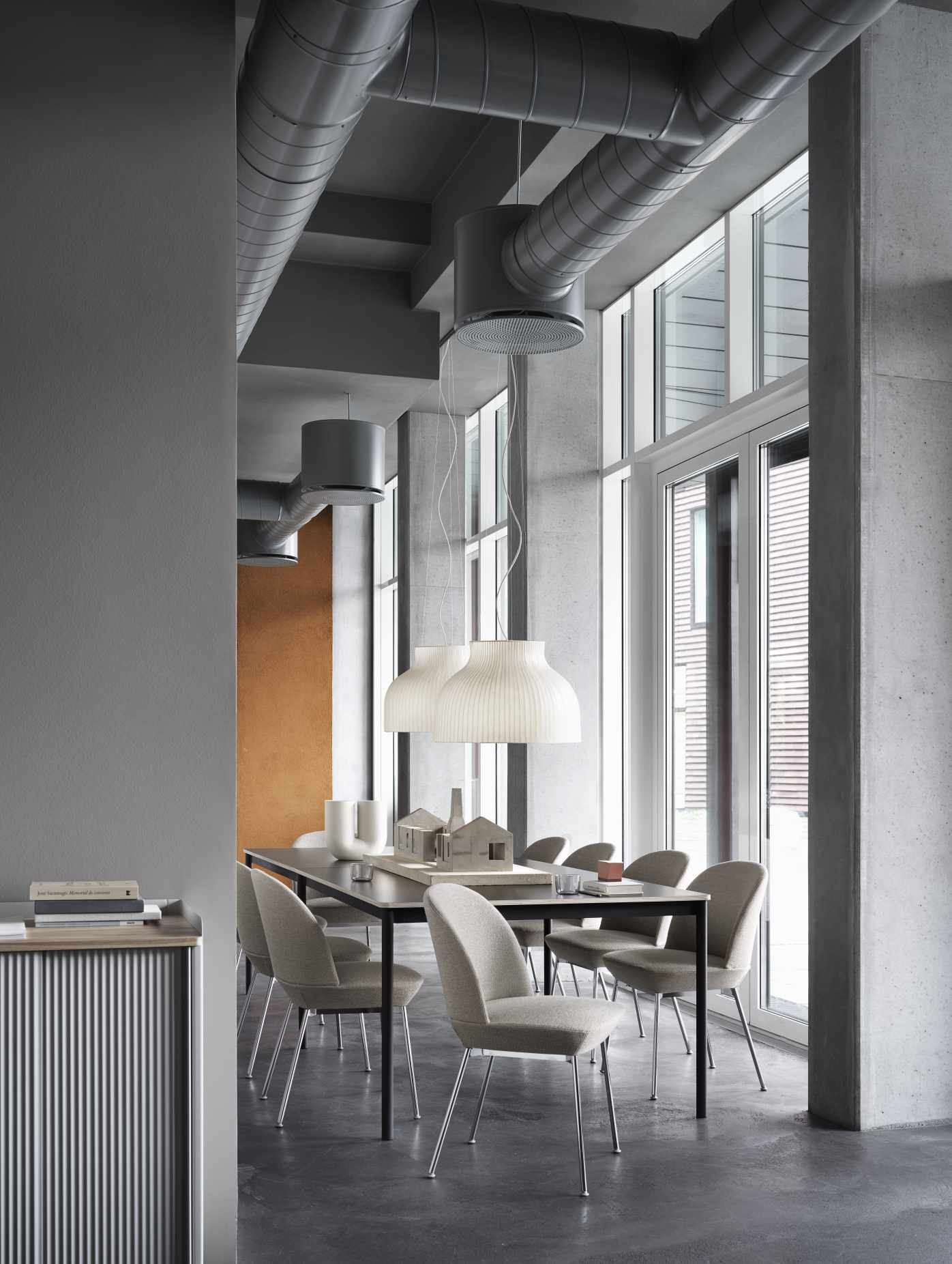 Helle Muuto Strand Pendelleuchte über Esstisch in modernem Interieur mit großen Fenstern.
