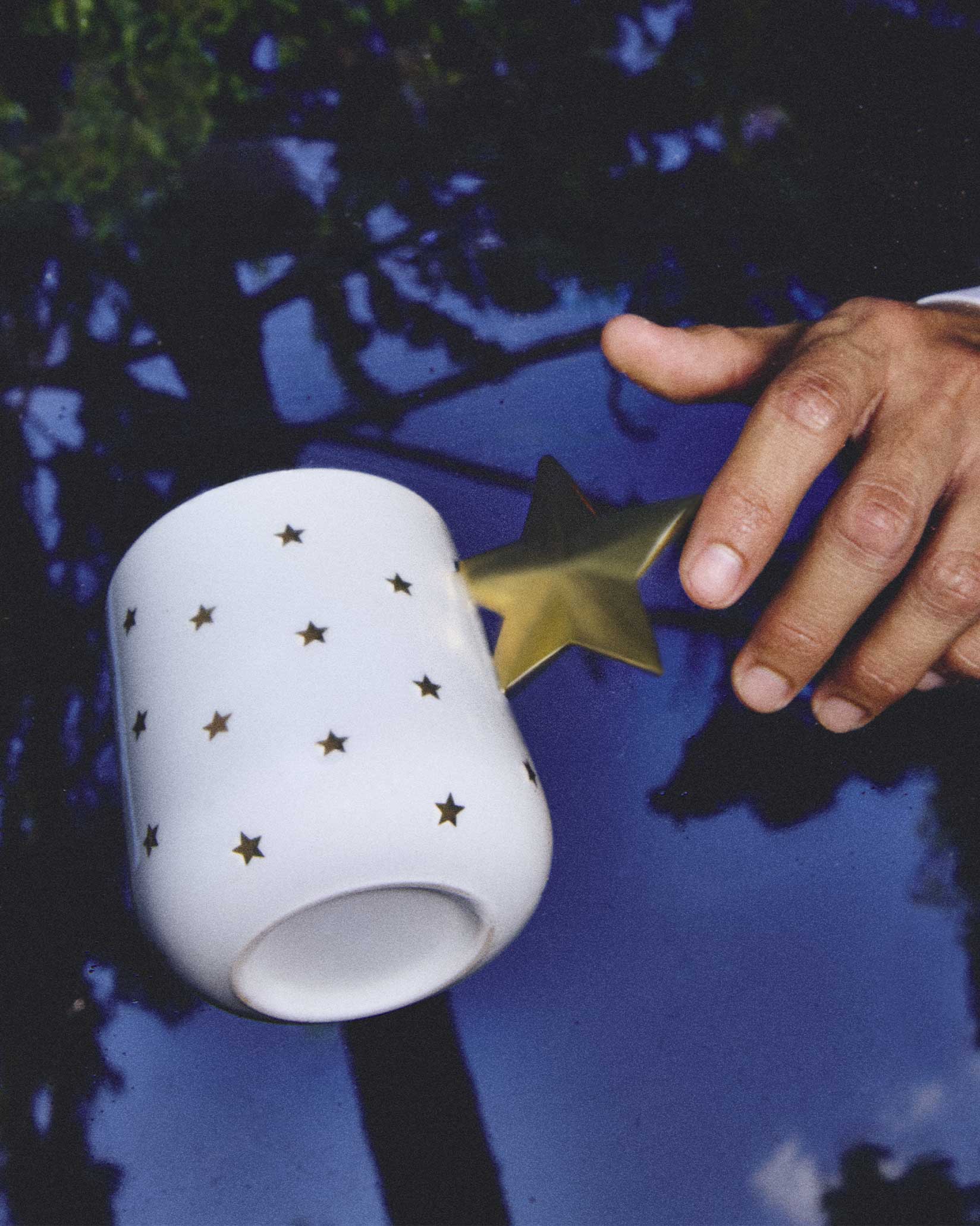 NZ01 Delight Mug Tasse Alessi mit goldenem Stern-Henkel und Sternenmuster auf blauem Untergrund.