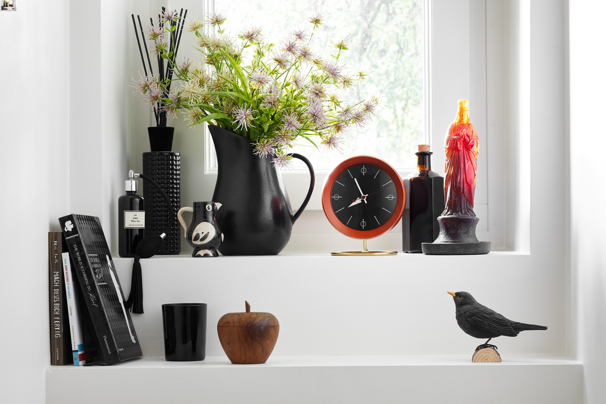 Nahaufnahme der Vitra Chronopak Tischuhr in Orange, Teil einer Dekoration auf einem weißen Regal.