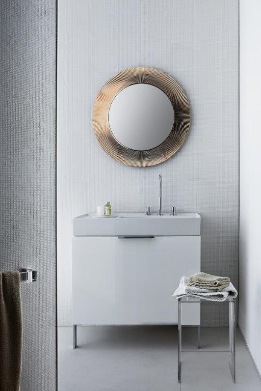 All Saints Spiegel von Kartell über Waschbecken im modernen Badezimmer mit Handtuch und Hocker.