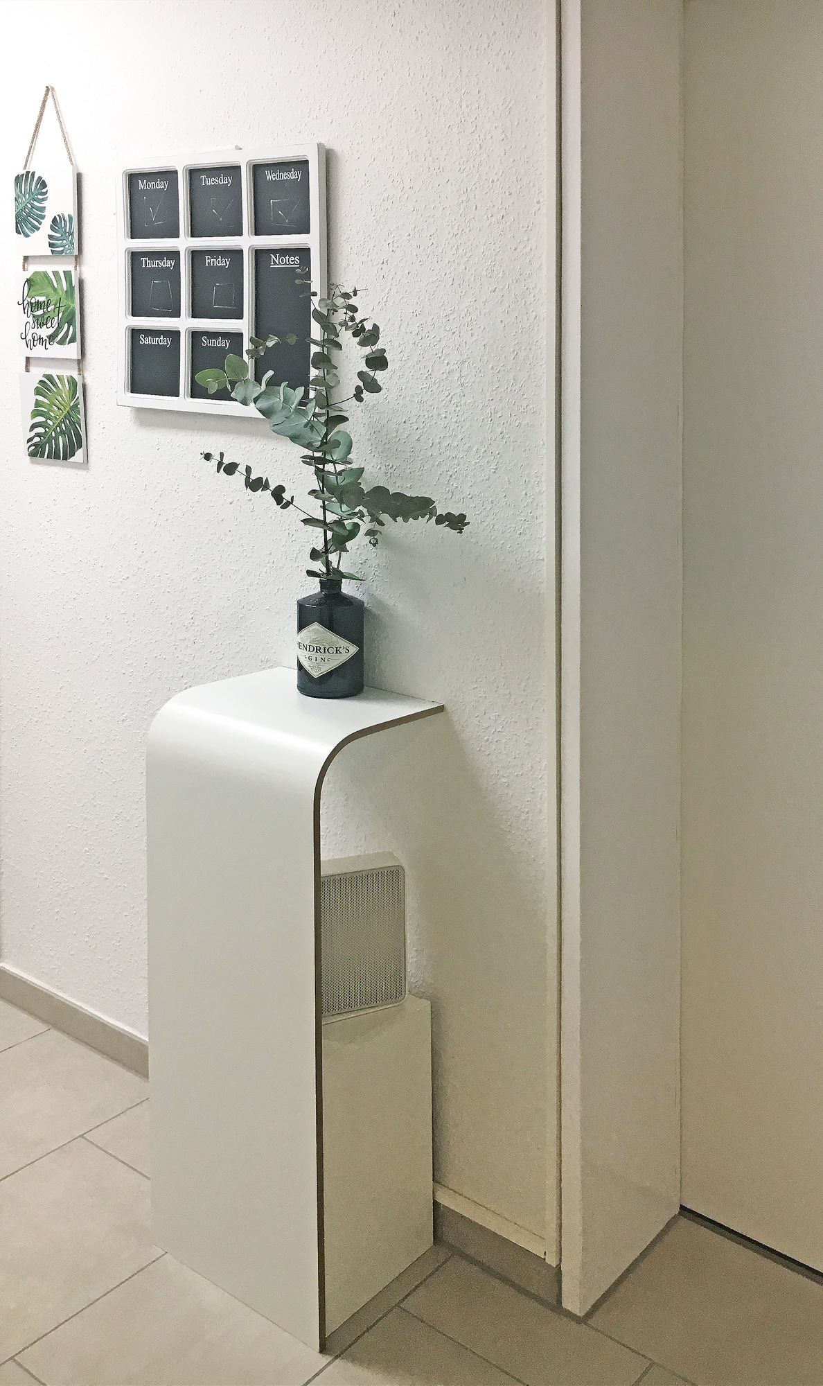 Weißes Tojo Fon Regal mit abgerundeten Kanten, dekoriert mit Gin-Flasche und Eukalyptus, minimalistisches Design.