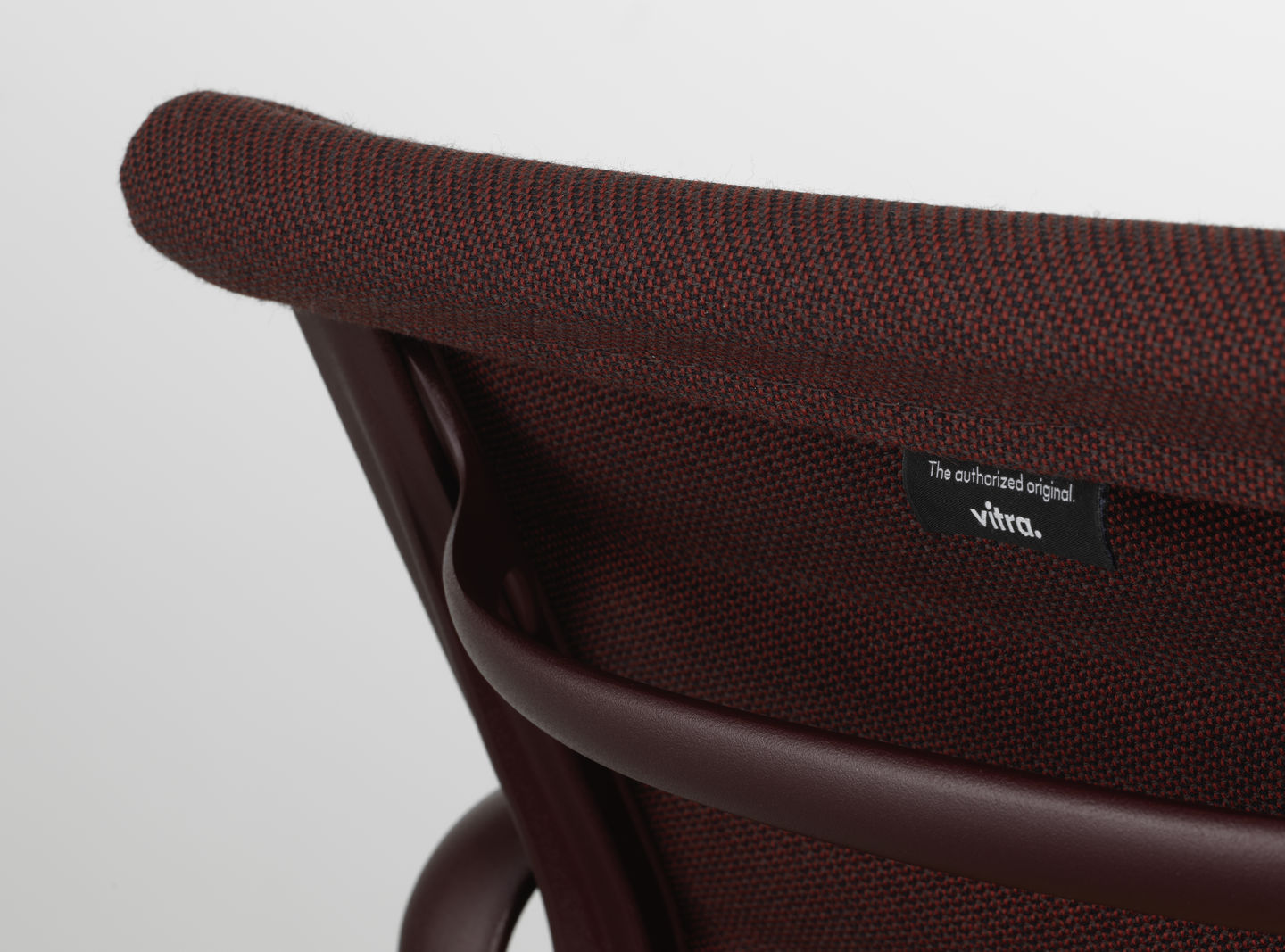Detailaufnahme Vitra EA 108 Aluminium Chair in Braun mit Stoffbezug und Vitra-Logo.