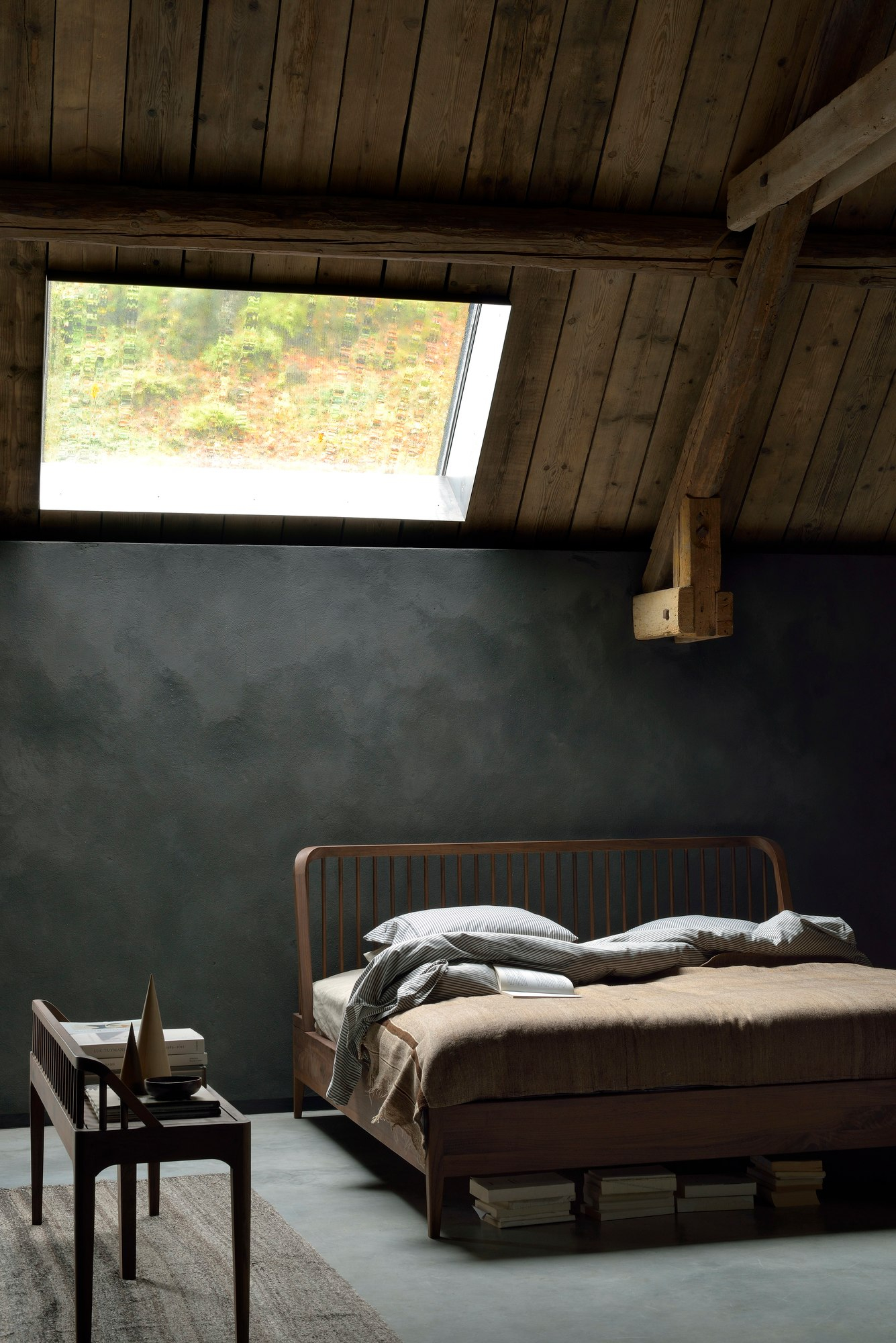 Spindle Bett von Ethnicraft aus Eiche im Schlafzimmer mit Dachfenster und Nachttisch.