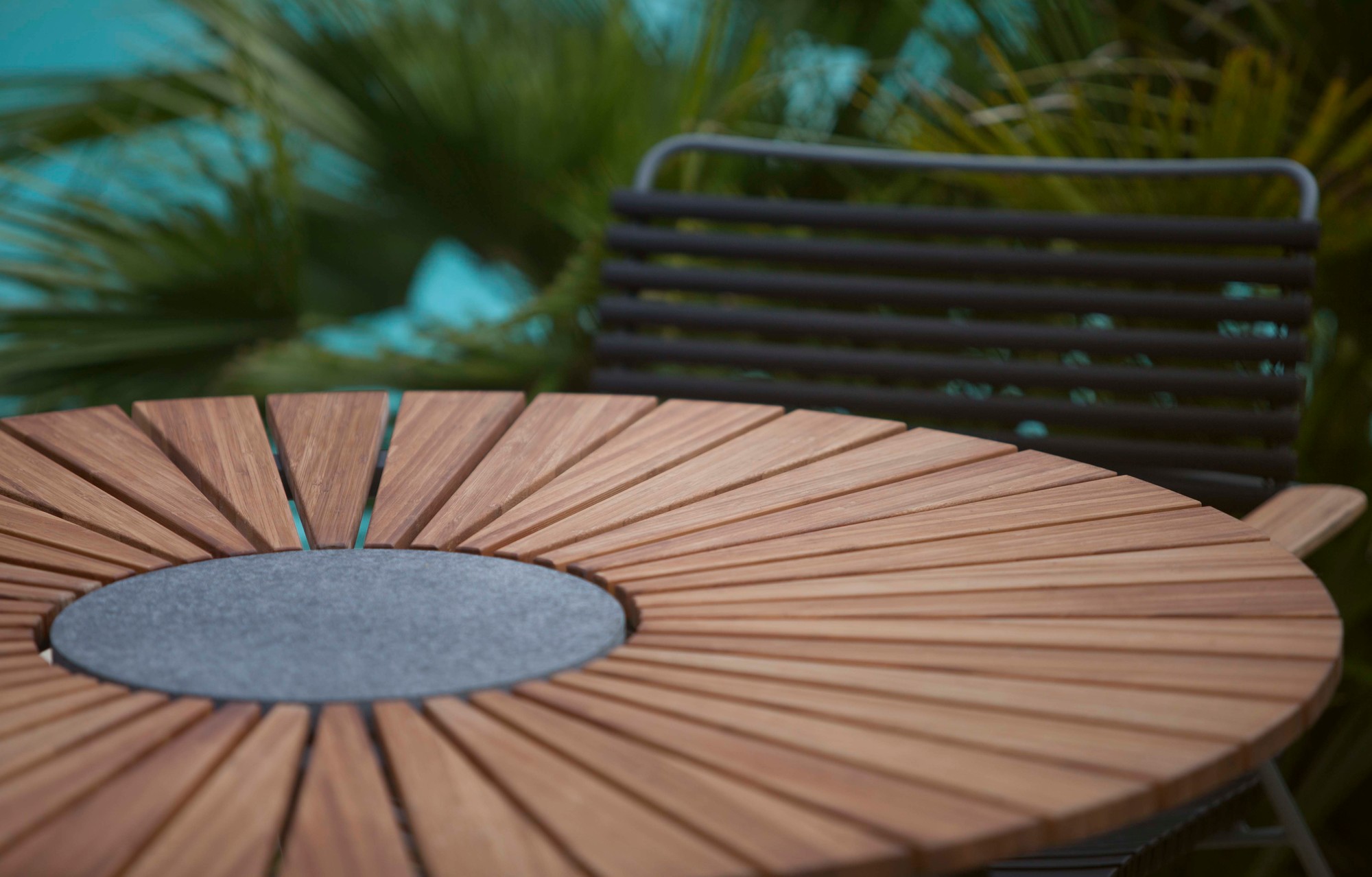 Detailaufnahme des Houe Circle Outdoor Tisch mit Holzlamellen und grauer Tischplatte.