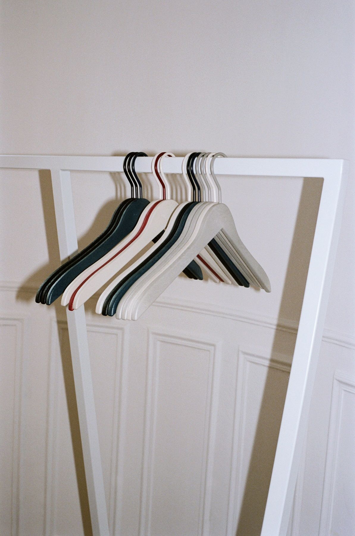 Hay Loop Stand Wardrobe Garderobe mit Kleiderbügeln in verschiedenen Farben vor weißer Tür.