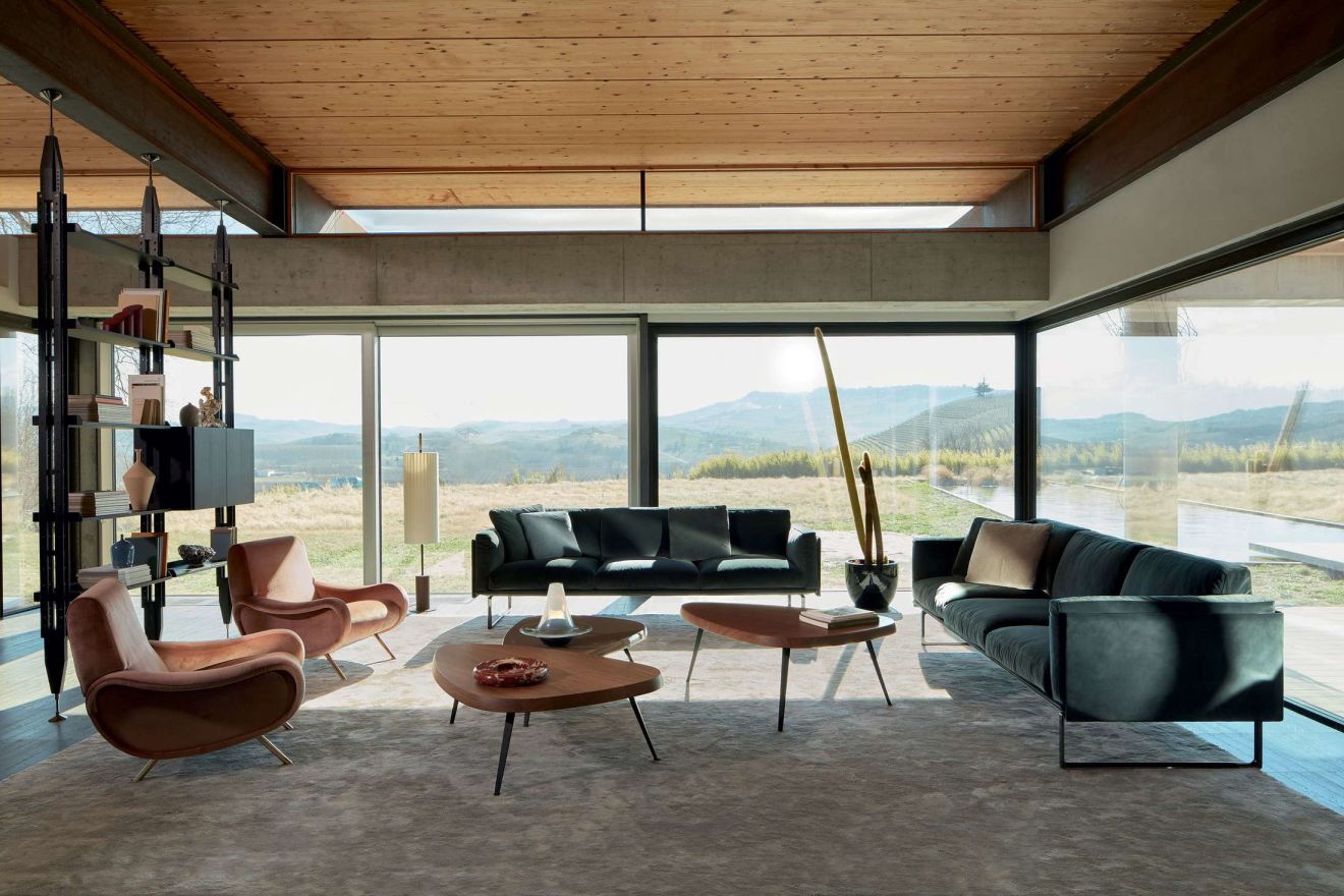 Wohnzimmer mit zwei Cassina Lady Sesseln, Sofas und Couchtischen vor Panoramafenster.