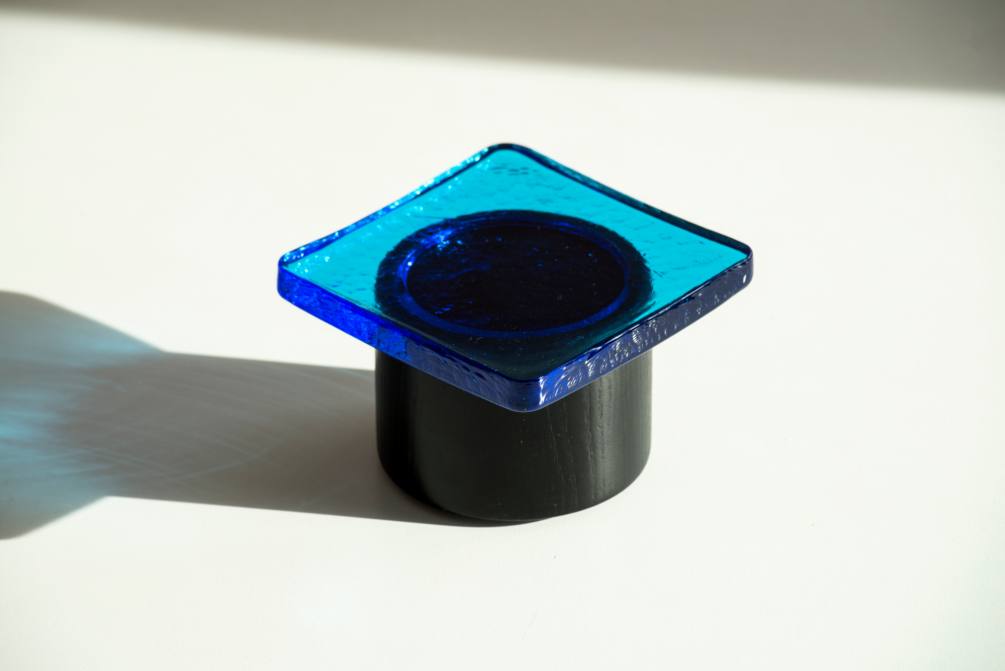 Pieduccio Schale Favius: Quadratische, blaue Glasschale mit Deckel auf einem zylindrischen, schwarzen Holzfuß.