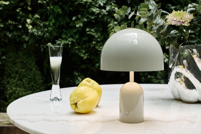 Weiße Tom Dixon Bell Akkuleuchte auf Marmortisch, moderne LED Tischleuchte für Innen und Außen.