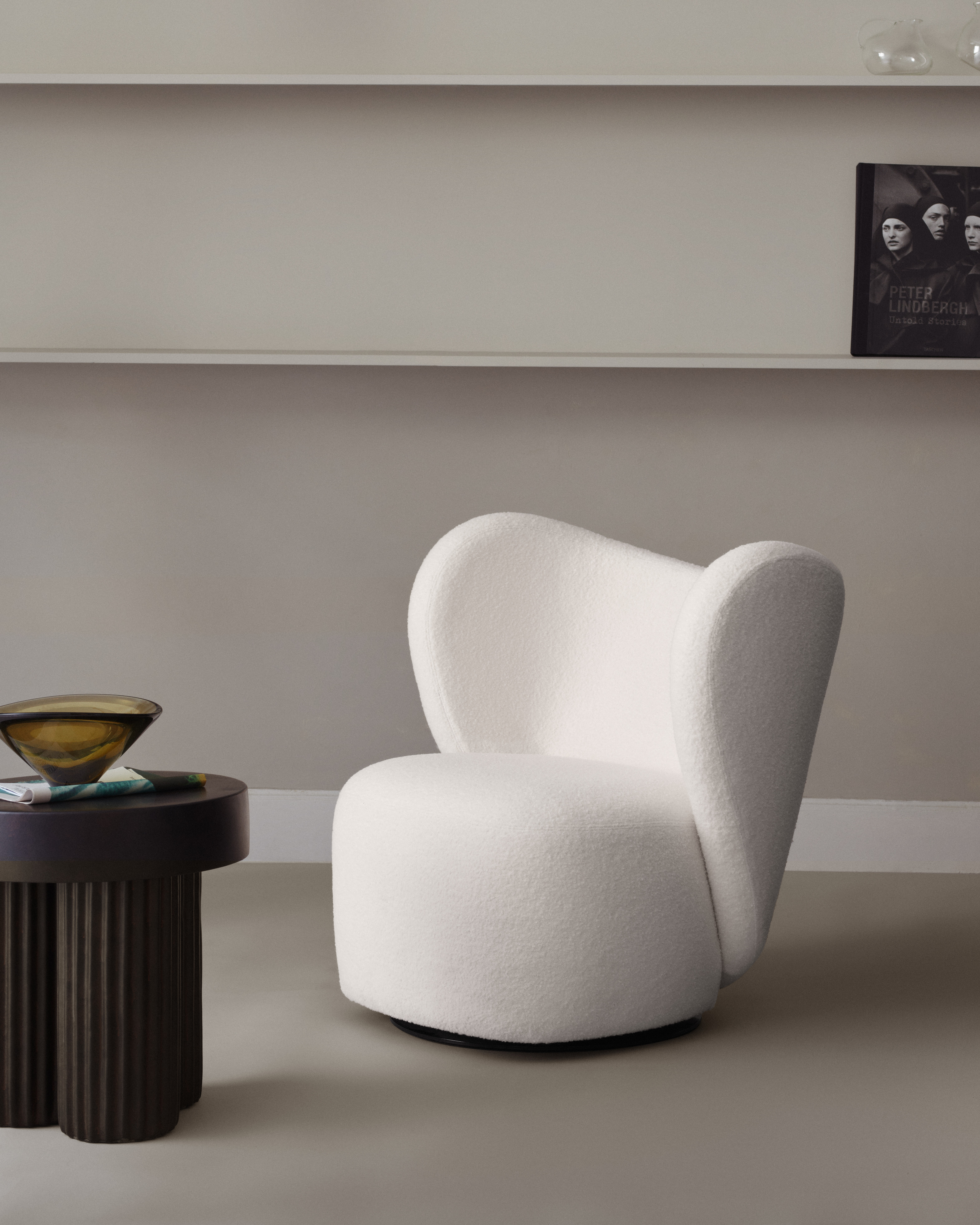 Gear Tall Side table von Norr11 aus dunklem Holz neben einem weißen Sessel.
