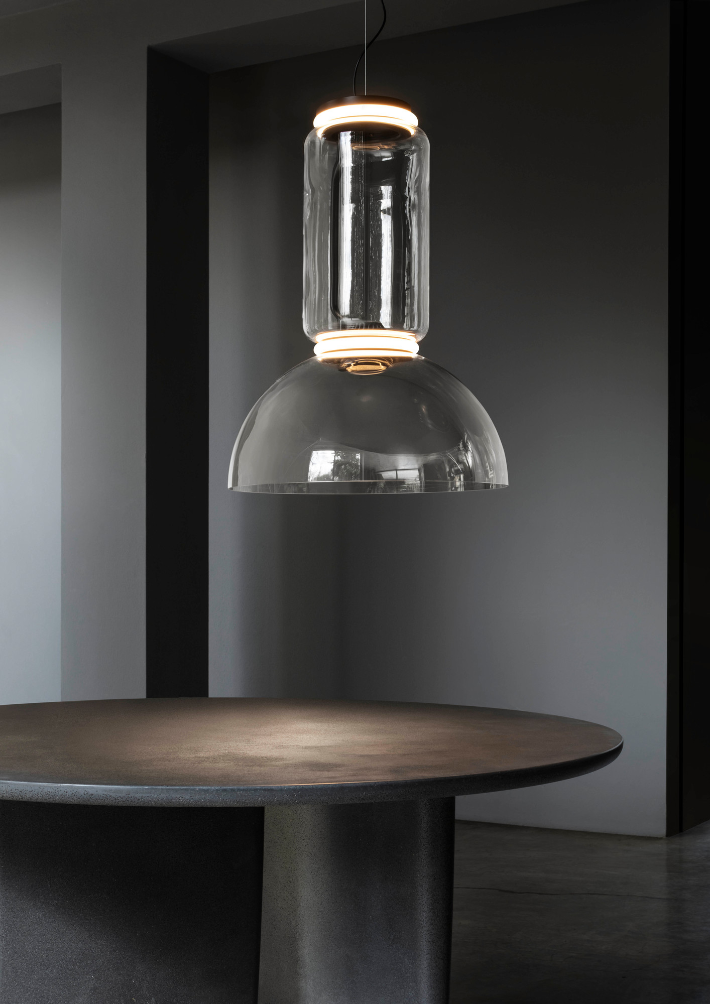 Noctambule Pendelleuchte von Flos: Moderne Hängelampe aus Glas mit LED-Beleuchtung über einem Tisch.