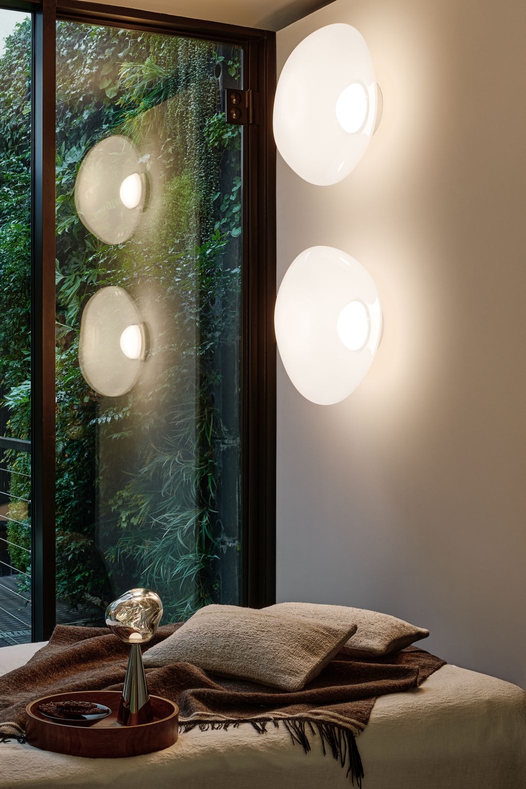 Nahaufnahme von zwei Tom Dixon Melt Wandleuchten in Opal-Gold an einer Wand.