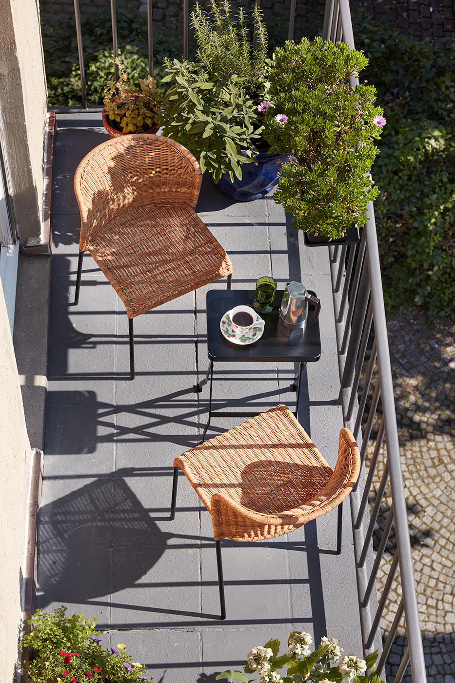Zwei Santa Lucia Rattanstühle von Richard Lampert auf einem sonnigen Balkon mit Tisch.