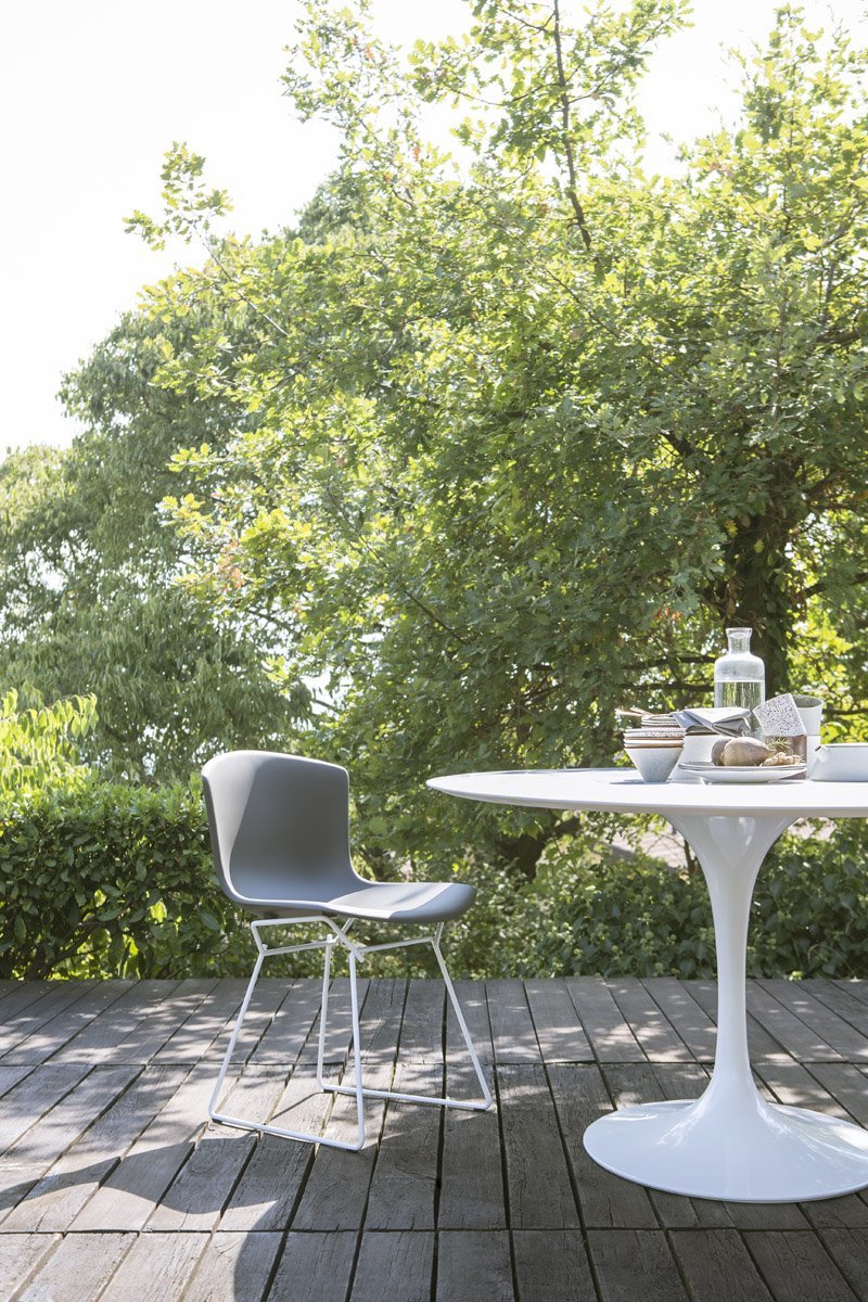 OUTDOOR Saarinen Tisch von Knoll International mit Stuhl auf Holzterrasse im Garten.