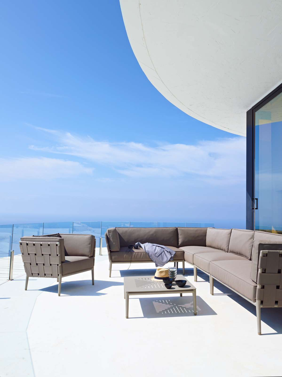 Hellgraues Conic Outdoor Modulsofa (2-Sitzer rechts) von Cane-Line auf einer Terrasse mit Meerblick.