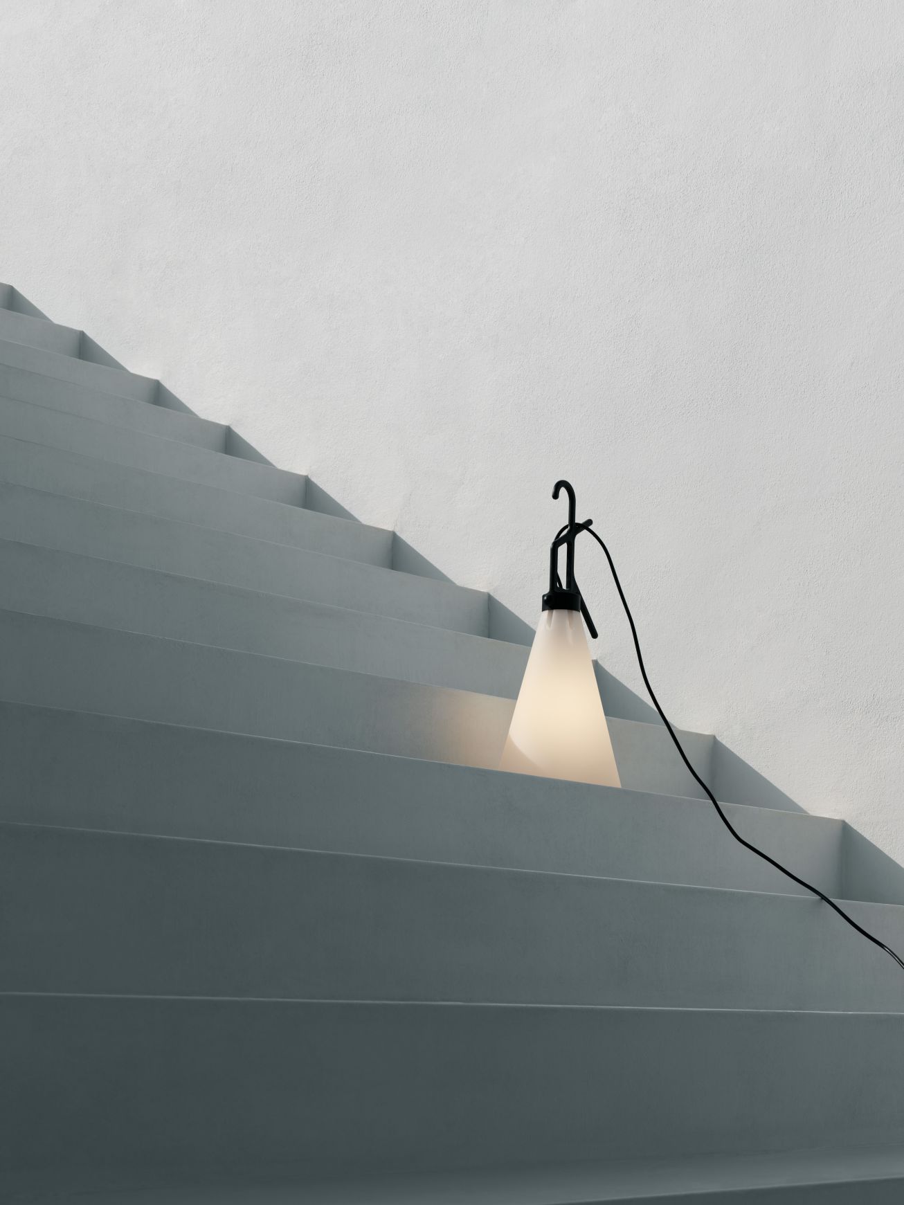 Moderne Tischleuchte mit schwarzem Gestell und weißem Lampenschirm auf einer grauen Treppe. Design Lampe für Wohnzimmer.
