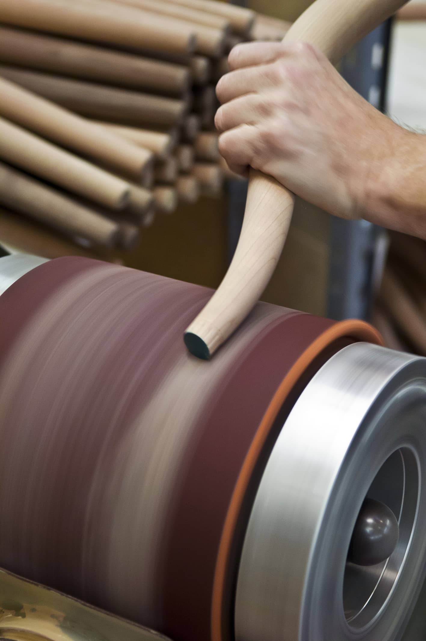 Hand schleift Holzstab auf Schleifmaschine. Herstellung von Holzprodukten, Möbelbau, Handwerk.