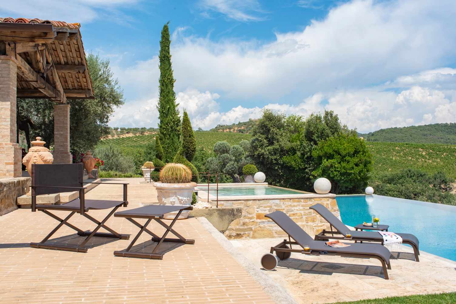 Terra Lounge Chair Sessel von Emu mit passendem Tisch und Sonnenliegen am Pool im Garten.
