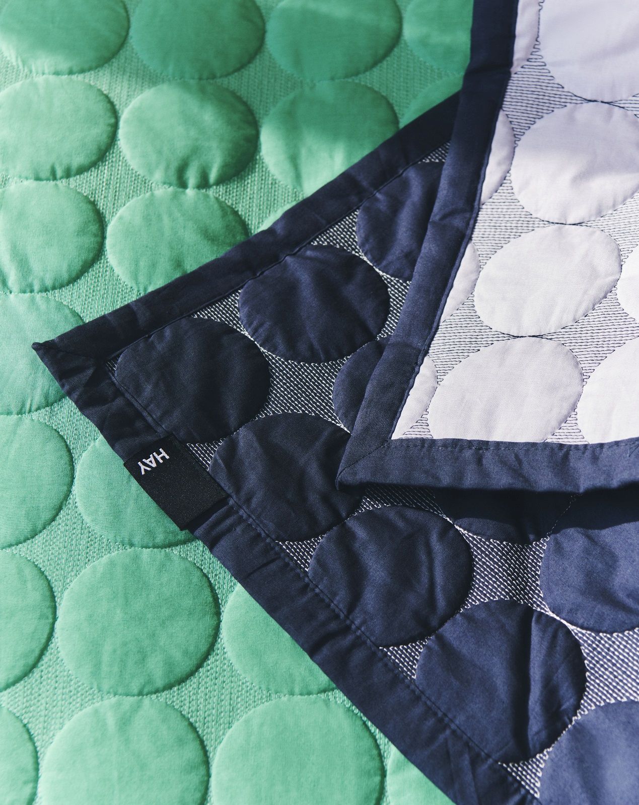Detailaufnahme der grünen und blauen Hay Mega Dot Tagesdecke mit organischem Punktmuster.