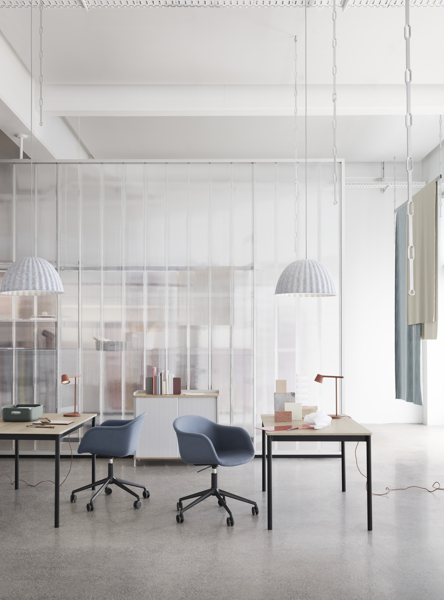 Zwei blaue, gepolsterte Fiber Armchairs von Muuto mit Drehfuß und Höhenverstellung an Schreibtischen.