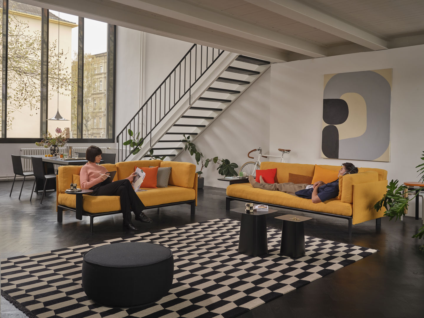 Wohnzimmer mit zwei gelben Sofas und zwei Anagram Anstecktischen von Vitra in Schwarz.