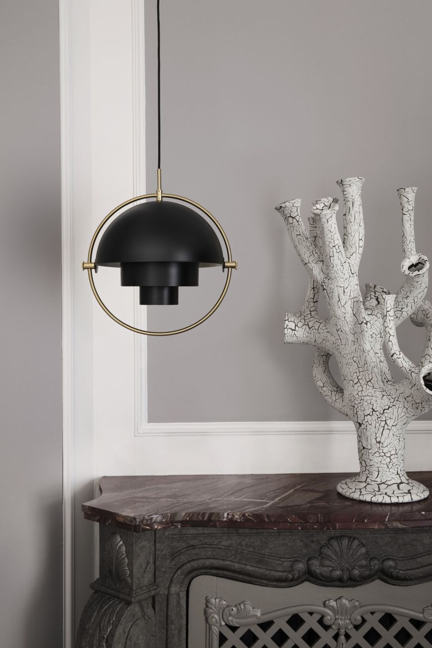 Schwarze Gubi Multi-Lite Pendelleuchte mit goldenem Rahmen über einem Marmorkamin, moderne Innenraumbeleuchtung.