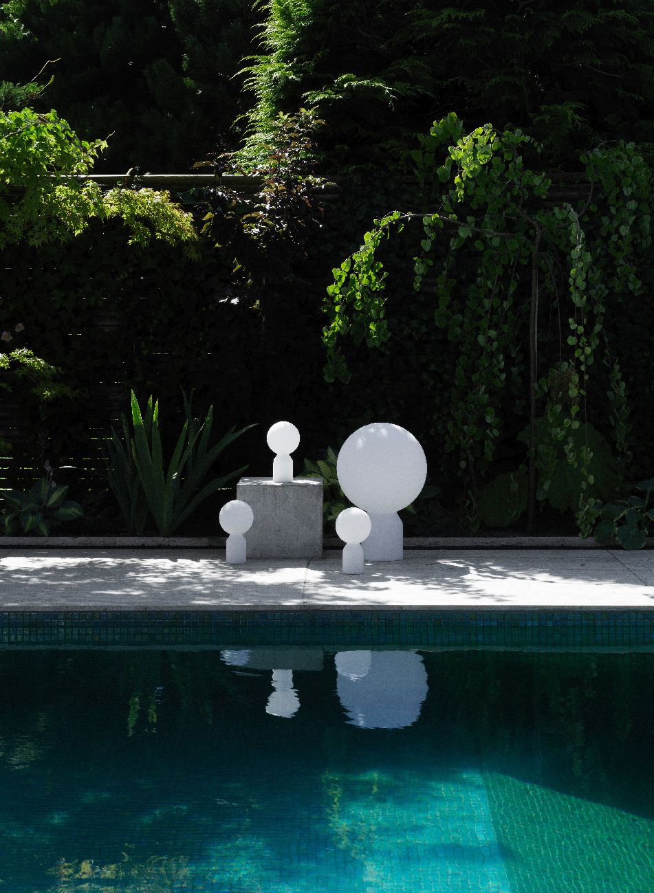 Normann Copenhagen Yo Lamp Small Tischleuchte als Akkuleuchte im Garten neben einem Pool, weiße moderne Gartenleuchten.