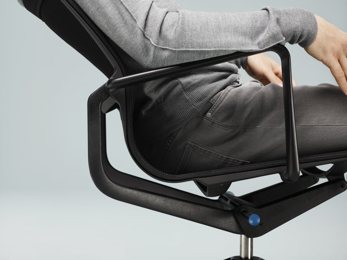 Detailaufnahme: Person sitzt auf schwarzem Physix Conference Stuhl von Vitra, ergonomischer Bürostuhl.