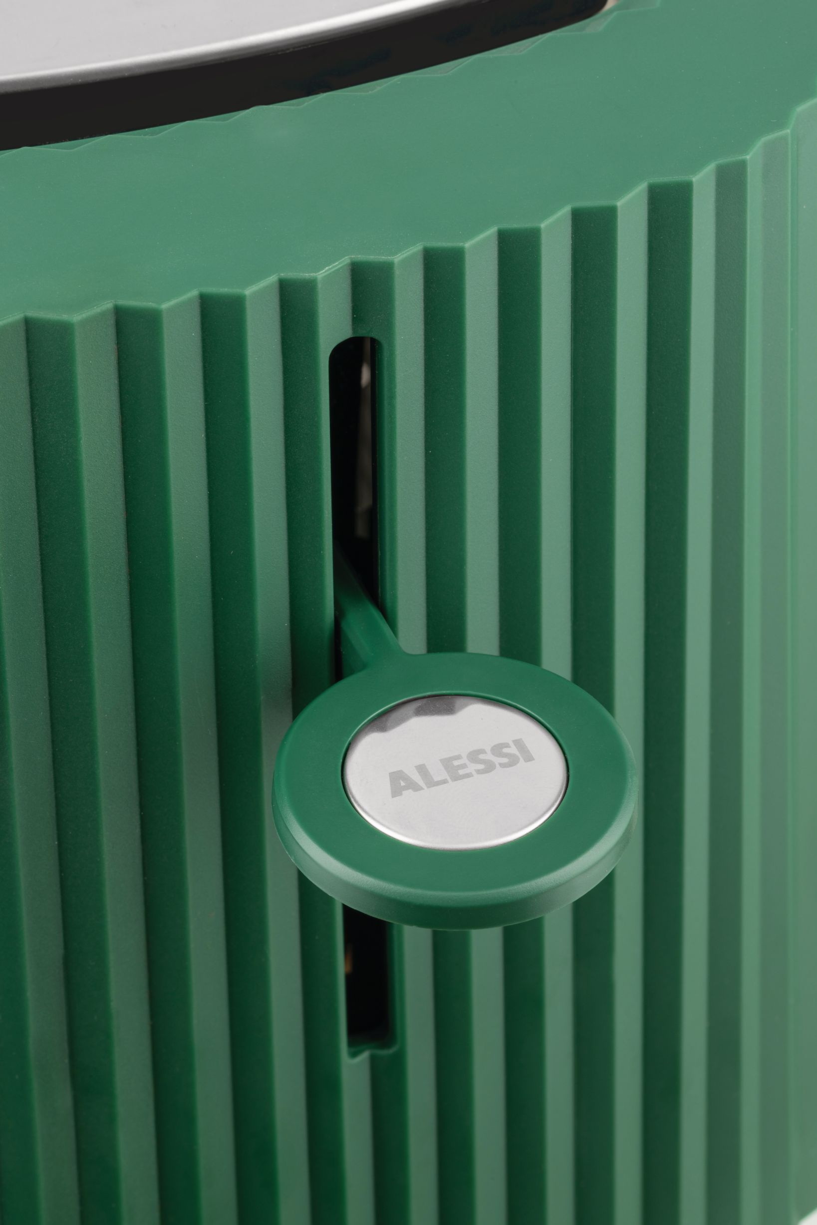 Grüner Alessi Plissé Toaster: Detailaufnahme des Toasters mit plissiertem Design und Alessi-Logo. Küchengerät für stilvolles Toasten.