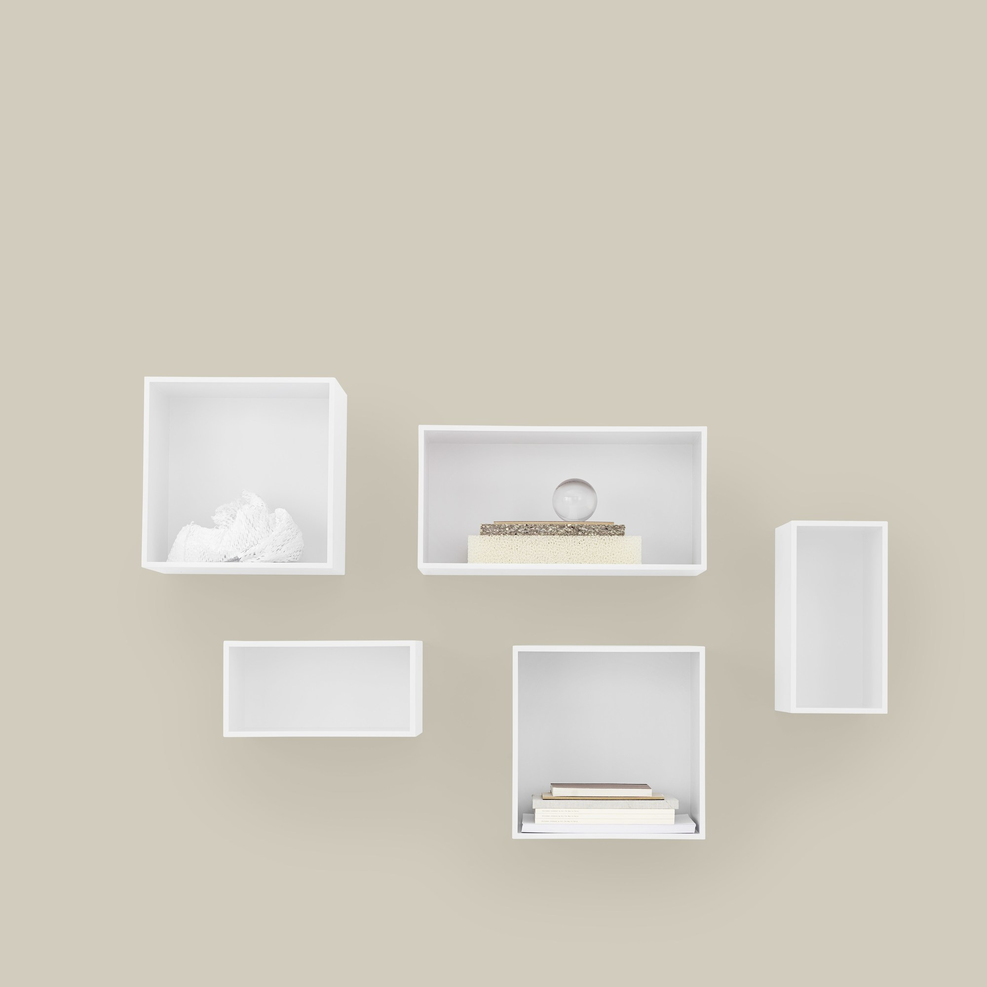 Weißes Muuto Mini Stacked Regalsystem 2.0 an beiger Wand mit Deko-Objekten und Büchern.