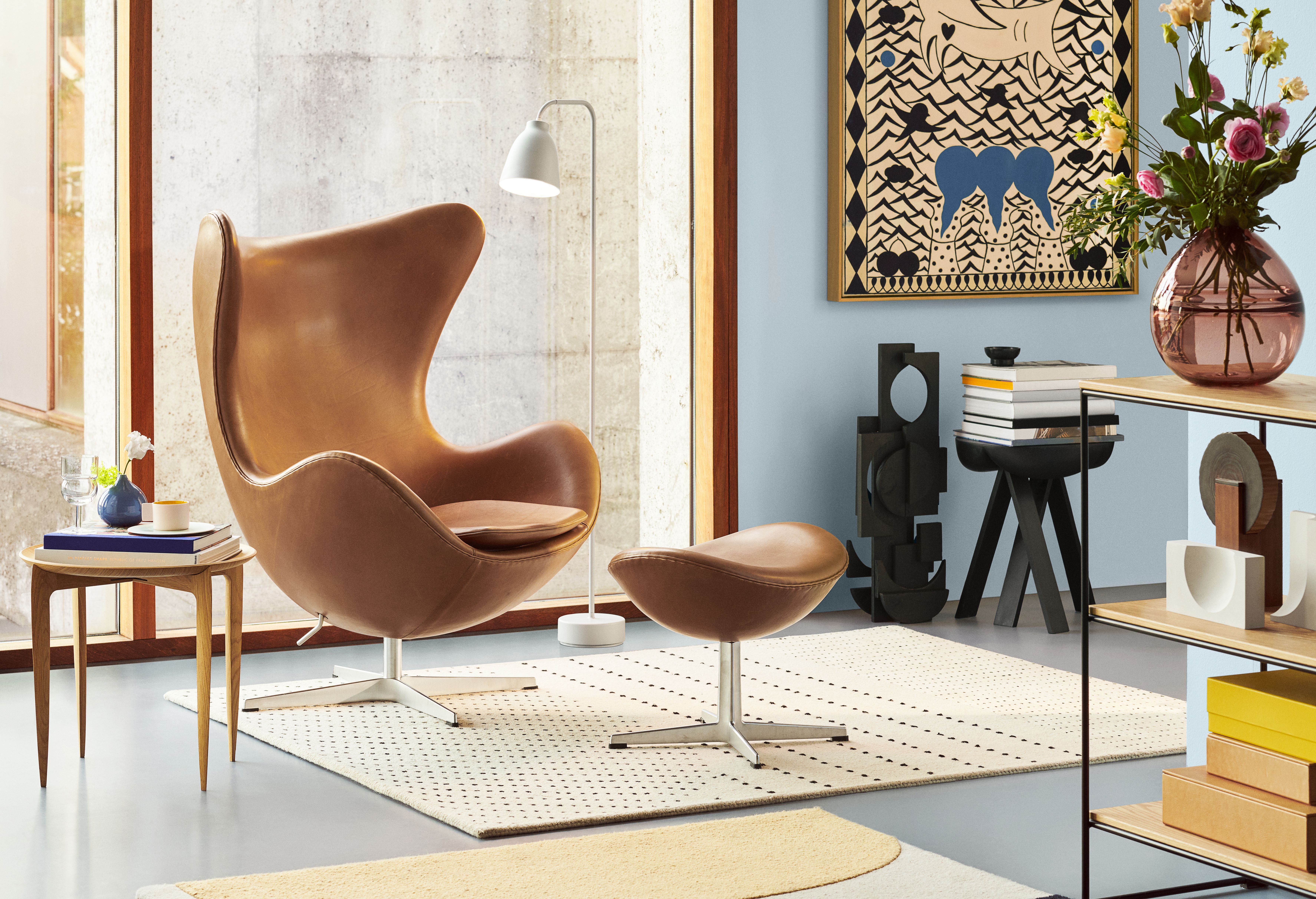 Brauner "Das Ei" Sessel von Fritz Hansen mit Hocker auf einem gemusterten Teppich in modernem Wohnzimmer.