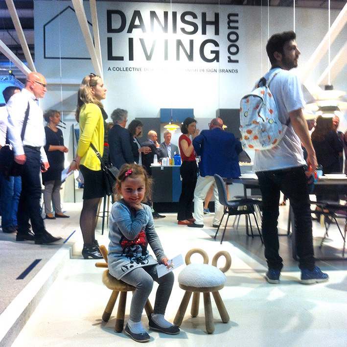 Mädchen sitzt auf EO Denmark Sheep Chair Kinderstuhl, ein niedlicher Hocker mit Schaffell-Sitzfläche.