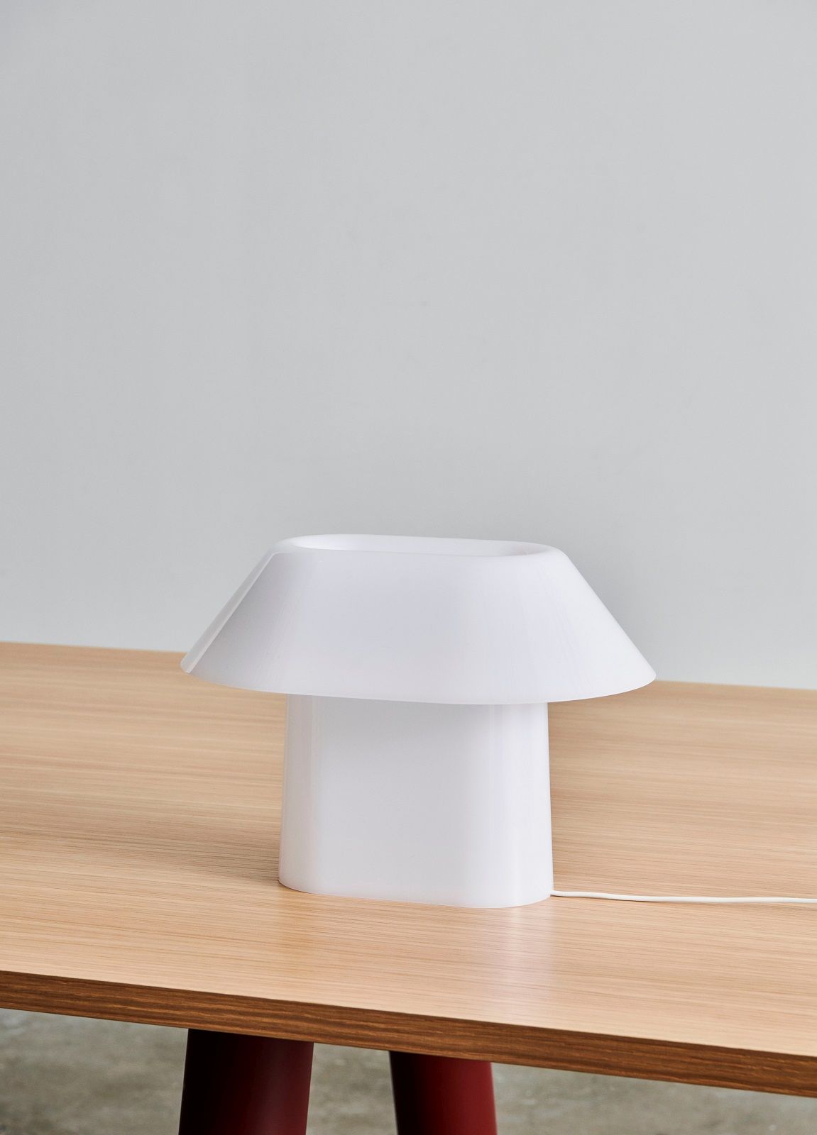 Weiße Drome Tischleuchte von Hay auf einem Holztisch, modernes Design für Wohnzimmer und Schlafzimmer.