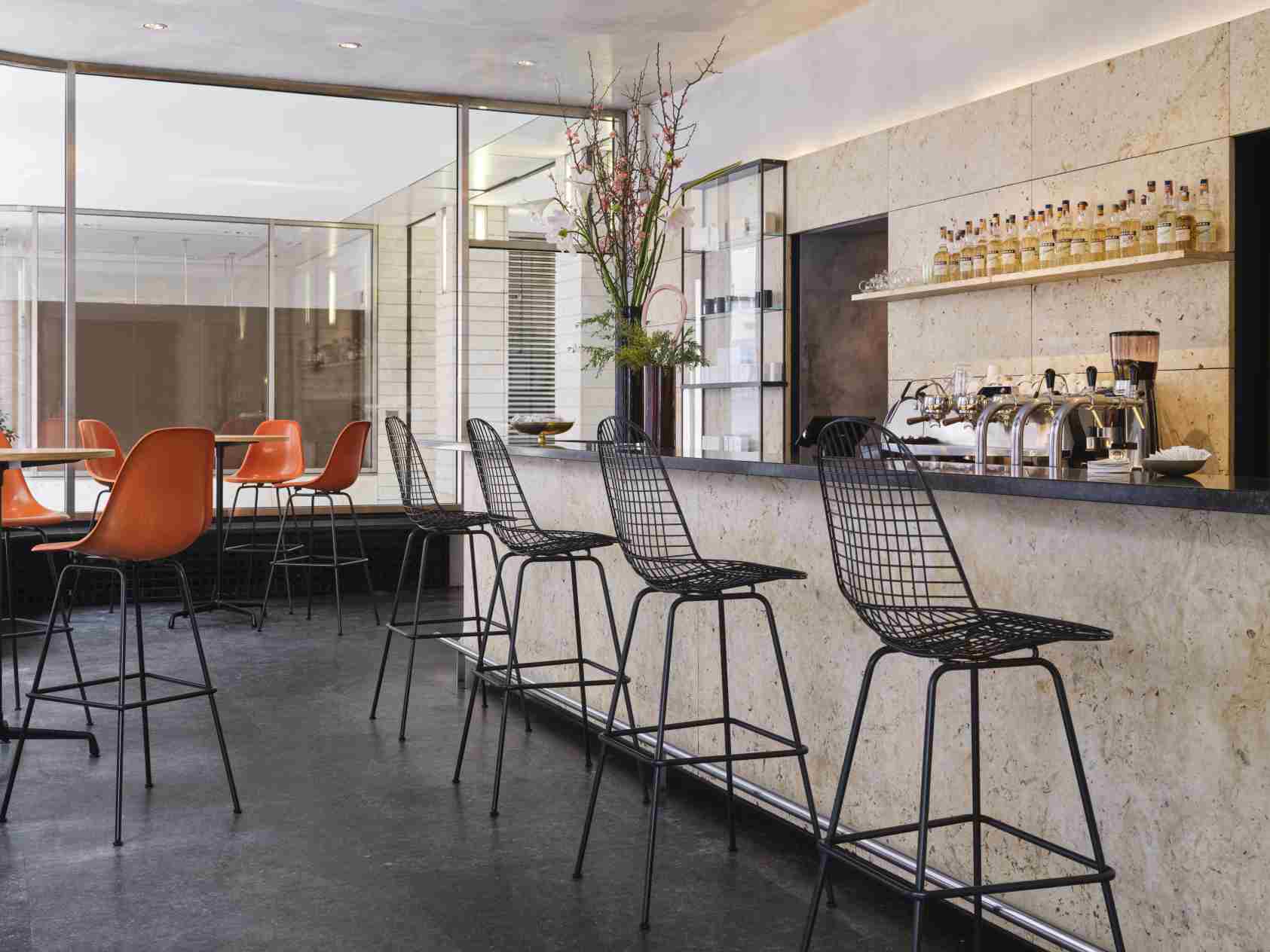 Eames Wire Bar Stool Barhocker High Vitra in einer modernen Bar, schwarzes Drahtgestell.