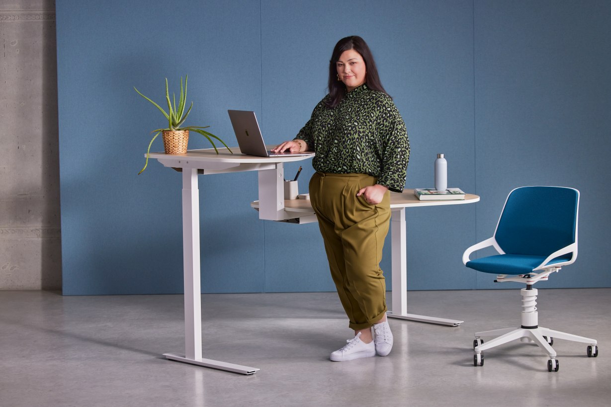Frau am höhenverstellbaren Schreibtisch mit Numo Task Bürodrehstuhl von Aeris im modernen Büro.