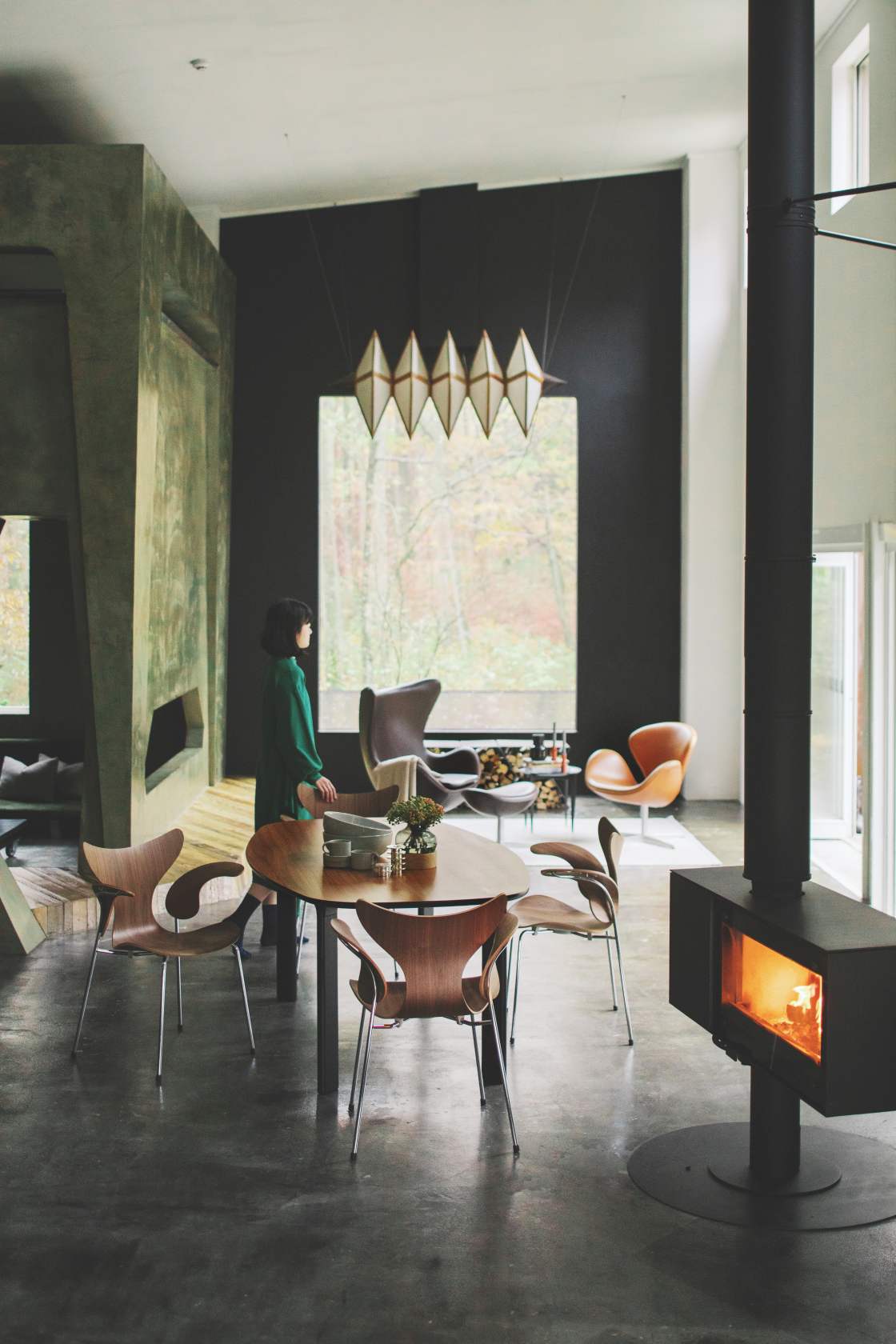 Innenaufnahme mit Fritz Hansen Lily Armlehnstühlen aus Holz um einen Esstisch in modernem Wohnraum.